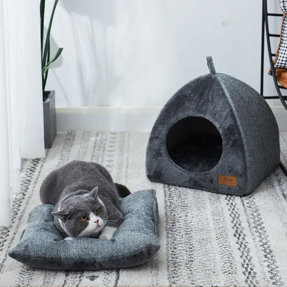 Gray cat lying on a matching cushion next to a gray pet bed in a home setting.