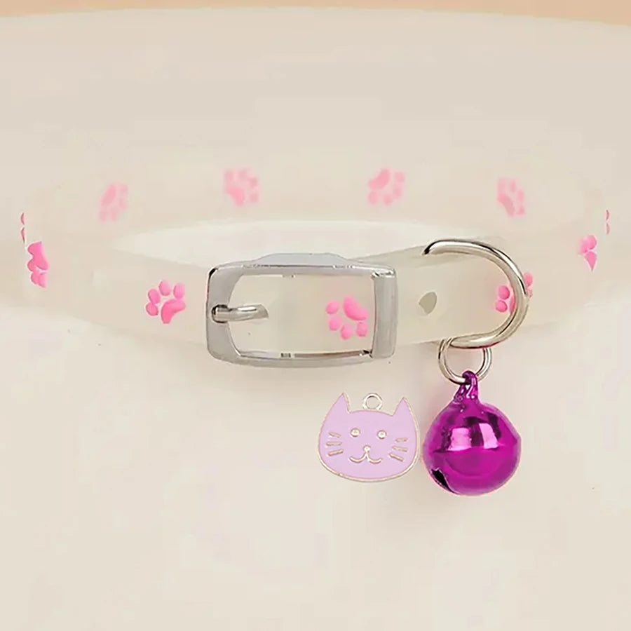 Cat-shaped keychain with a bell on a pink paw print background